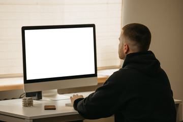 Remote work. A back view of a businessman works remotely using an all-in-one computer. A fellow working from home.