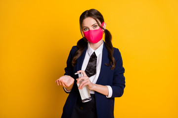 Portrait of her she nice attractive pretty lovely brown-haired schoolgirl wearing pink mask using sanitizer isolated on bright vivid shine vibrant yellow color background