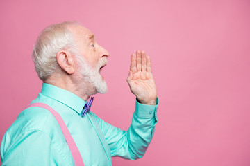 Profile photo of attractive grandpa looking empty space hand near open mouth yelling secret information people crowd wear mint shirt suspenders bow tie isolated pink pastel color background