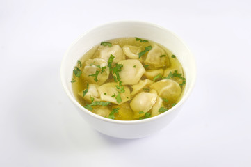 dumplings in the broth with parsley in a white plate on a white background