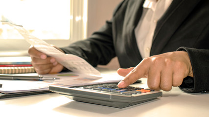 Close-up of businessmen or accountants holding a pen and pressing on the calculator to calculate business information, accounting documents, business ideas.