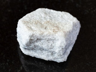 closeup of sample of natural mineral from geological collection - unpolished Marble rock on black granite background from Moscow region, Russia