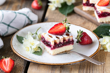 piece of tasty pie with strawberries on a white plate on ooden table