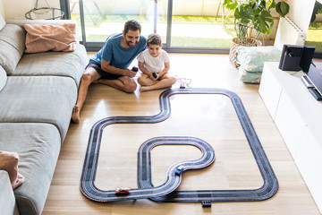 Father and son playing car races at home