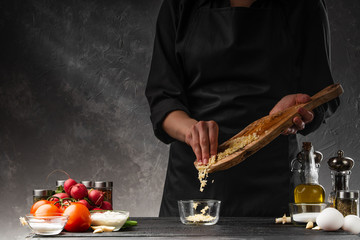 The cook sprinkles fresh chopped garlic to prepare garlic sauce. Against the background of...