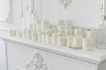 White candles on decorated mantelshelf