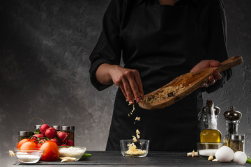 The cook sprinkles fresh chopped garlic to prepare garlic sauce. Against the background of...