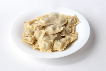 on white background. A plate of white color is round, several ravioli lie on it and steam comes. There is a shadow. Close-up