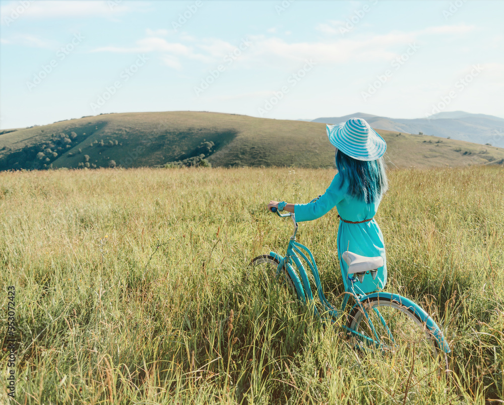 Poster unrecognizable romantic girl walking with bicycle in summer meadow.