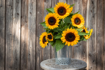 Beautiful sunflower bunch in front of a wooden wall with lots of space for text (copy-space).
