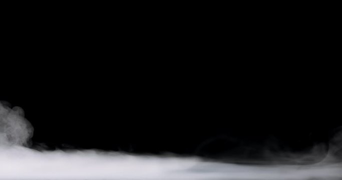 low lying fog rolling in over the bottom of the frame against a black background.