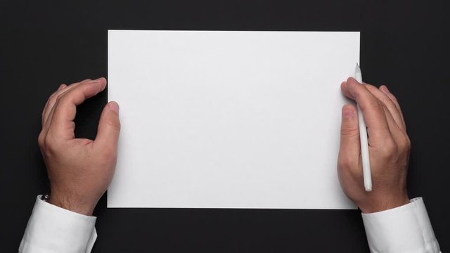 top view of a blank sheet of paper and a businessman's hands on a black table, white shirt and wrist watch