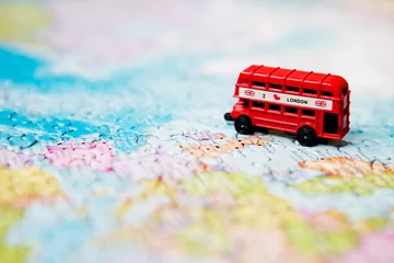 Foto auf Glas Reise- und Bildungskonzept. Touristenattraktionen und Andenken an den roten Londoner Bus auf Weltkartenhintergrund von Rätseln für Reisende. Platz kopieren © Liudmyla