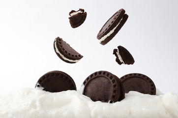 Closeup of falling delicious chocolate sandwich cookies and sweet glaze against white background
