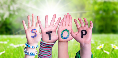 Children Hands Building Colorful English Word Stop. Sunny Green Grass Meadow As Background