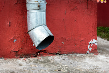 Old drain pipe on the brown brick wall. Downspout