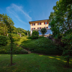 Fototapeta na wymiar Beautiful house in the middle of the greenery with a modern reinforced concrete connection and a large window. Dream garden