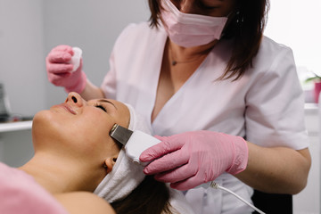 Woman getting laser and ultrasound face treatment in medical spa center