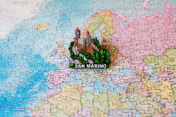 Tourist attractions and souvenir of San Marino on background map of world of puzzles for travelers. Copy space
