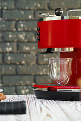 Fototapeta na wymiar Red coffee machine with a glass on kitchen counter