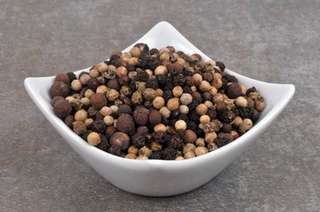 Ramequin de poivre en grains en gros plan sur fond gris