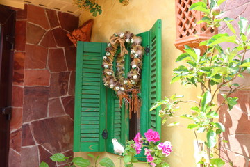 Decorative window with green wooden shutters on the wall of a country house