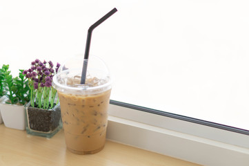 Closeup glass of ice coffee with flower pot in the coffee shop