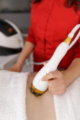 The doctor does an RF lifting procedure on the belly of a woman in a beauty salon.Ultrasound cavitation body contouring and sculpting treatment, anti-cellulite and anti-fat therapy in beauty salon.
