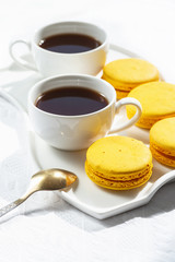 Macaroons and coffee cup on white wood table.