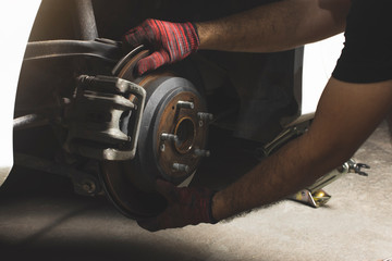 Car mechanic inspected disk brake and caliper at wheel hub of car. - obrazy, fototapety, plakaty