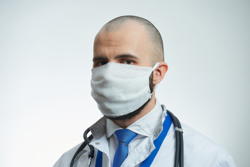 A close portrait of a doctor in a protective face mask. A doctor in a white lab coat with a stethoscope. 
