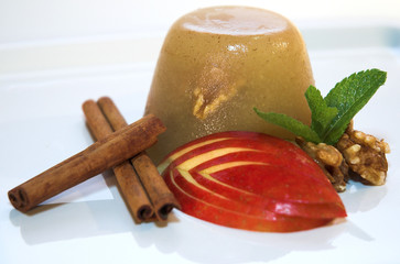 Apple fruit aspic with nuts, cinnamon and mint on a white plate