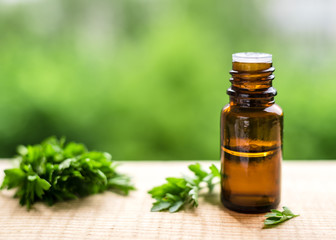 aroma Parsley oil in a dark glass bottle on a wooden table and natural green background