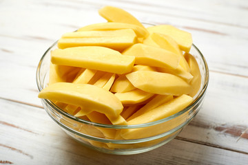 Sliced potatoes in a plate on a wooden background. Preparing potatoes for cooking.