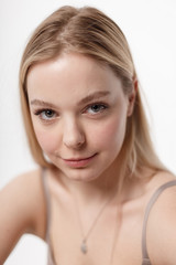 pretty caucasian girl with naked shoulders looking at camera. beauty portrait, close up. beautiful woman with perfect clean skin on white studio background. soft focus on her face