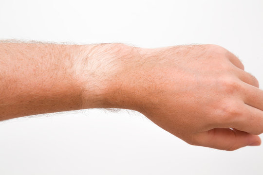 Young man showing not tanned arm skin from watch. Gray background. Problem of daily using watch in summer time. Closeup.