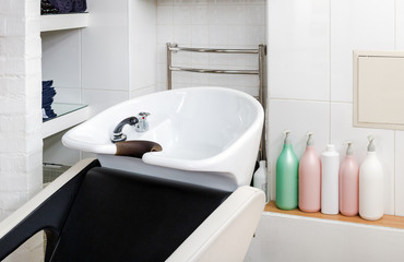 Hairdressing bowl, hair washer equipment. Beauty Salon Interior with copy space. Hair wash sink for washing hair in beauty salon or Barber shop, shampoos, towels. Hairdresser stylist work space