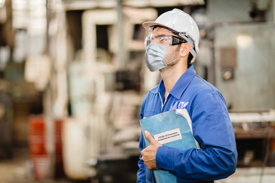 Worker Wearing Face Shield Or Disposable Face Mask With Coronavirus(Covid-19) Prevention Guidlines Manual Hand Book For Guidance Rule To Healthy Work In Factory.