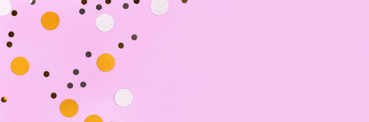 Golden and silver confetti scattered on a purple pastel background. Festive concept.