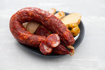 Fototapeta premium portuguese smoked sausage, olives and corn bread broa on ceramic background