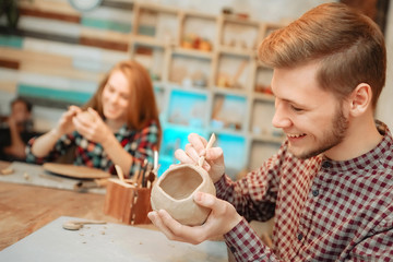 Young man and woman works in pottery and laughs. Sculpting from clay.