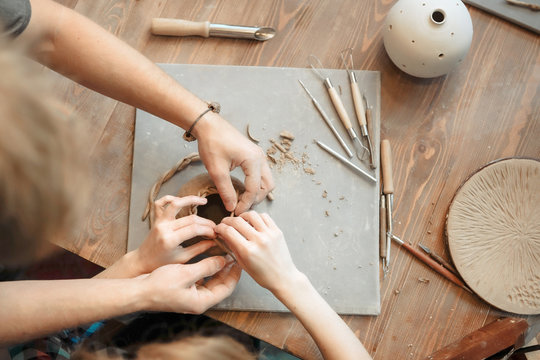Top view of hands sculpting a clay vase at the table. Sculpting tools. Pottery workshop.