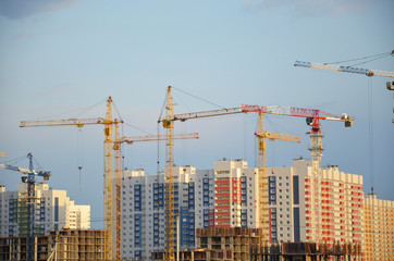 Fototapeta premium Inside place for many tall buildings under construction and cranes under a blue sky working on place with tall homes