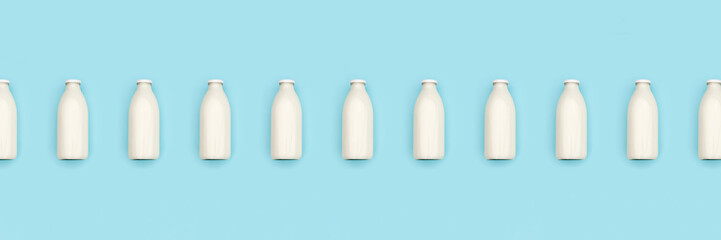Glass bottles of milk in a row on blue background. Flat lay Top view Banner Copy space