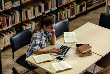 Young female student study in the library using laptop for researching online.	