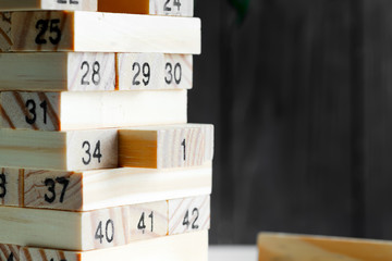 Wooden creative constructor from blocks with numbers against black background. Jenga game for earning, developing and education.