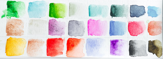Watercolor paints multicolored pattern on a white paper as a picture background.