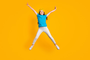 Fototapeta na wymiar Full length photo of crazy little lady jump high up good mood spread hands legs star shape figure wear casual blue t-shirt headband trousers shoes isolated yellow color background