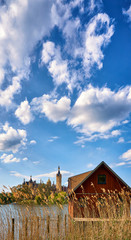 Boathouse with reeds and Schwerin Castle in the background. Vertical panorama with clouds and blue sky.