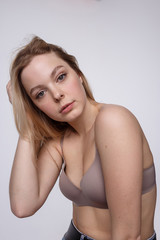Obraz premium beauty portrait of plump caucasian woman with long blond hair posing in beige lingerie on white studio background. model tests of young girl in bra. attractive female with clean skin